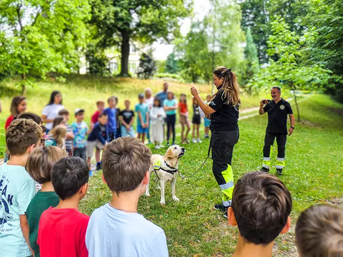 RDA zu Besuch im Hort: Einsatzleiterin Romana Rausch erklärt mit Labrador Gino Kindern den richtigen Umgang mit Hunden